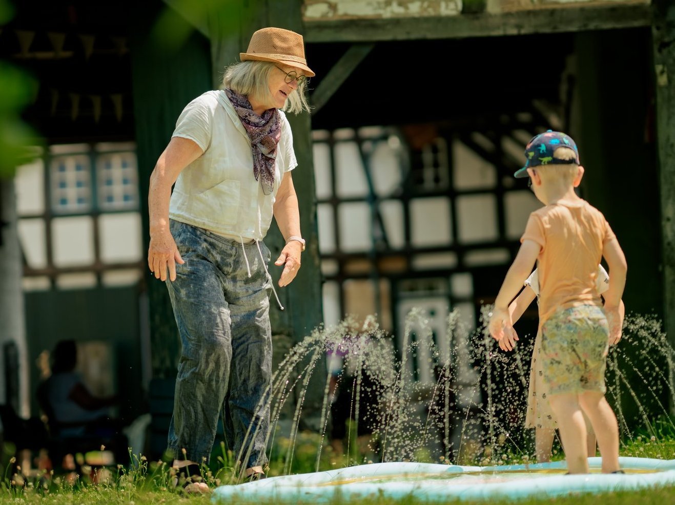 Eine Frau spielt mit zwei Kindern in einem Planschbecken.